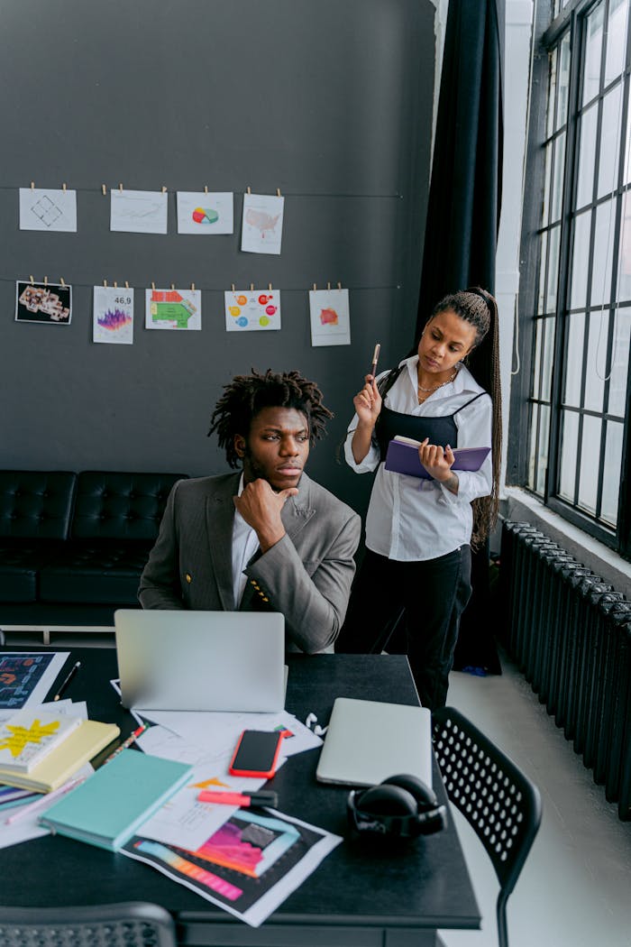 Two professionals discussing ideas in a contemporary office with tech and art supplies.